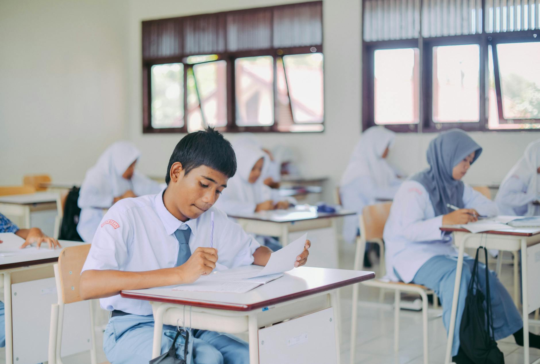 Siswa belajar bersama guru di kelas modern dengan papan tulis digital.
