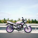 Mobil sport berwarna merah melaju cepat di jalan raya saat matahari terbenam