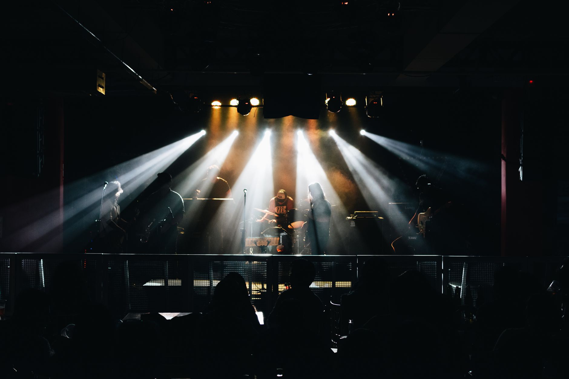 Seorang gitaris memainkan melodi akustik di panggung lampu sorot, mengekspresikan semangat musik